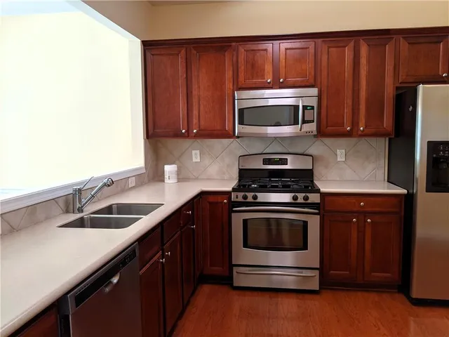 a kitchen with granite countertop wood cabinets stainless steel appliances and a sink