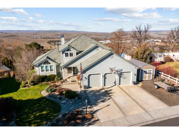 a view of a white house next to a yard with mountain and ocean view