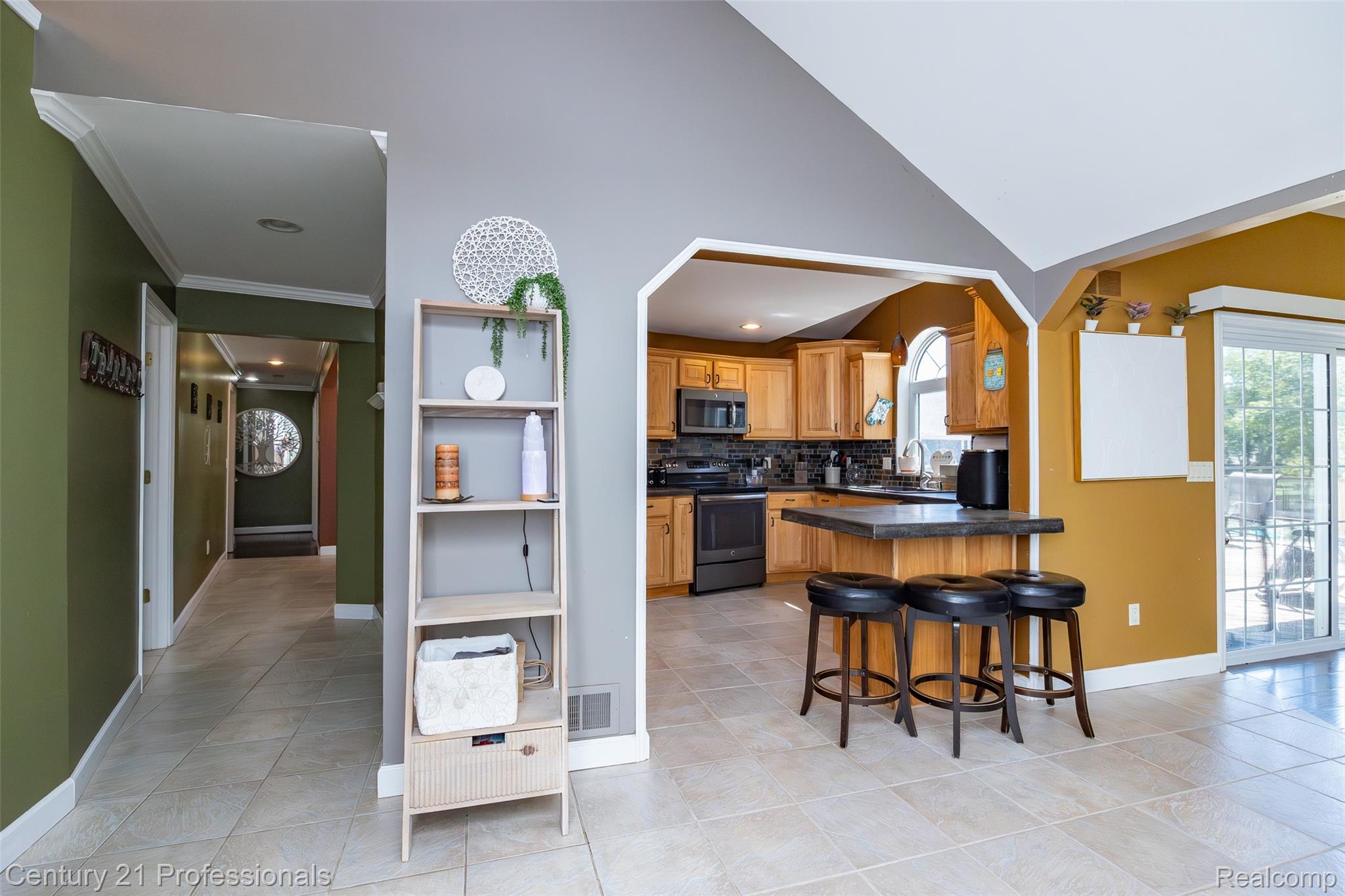 3251 Mann Road Clarkston, MI 48346 - Photo 16 of 40 Kitchen with wood cabinetry, black appliances, a peninsula with seating, and a tile backsplash