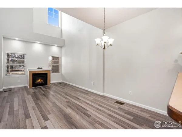 a view of an empty room with wooden floor and fireplace