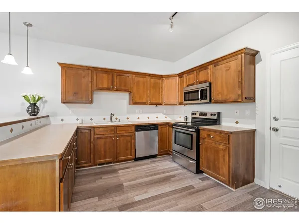 a kitchen with stainless steel appliances granite countertop a sink a stove a microwave a sink a refrigerator white cabinets and wooden floor