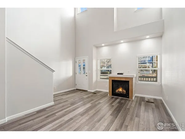 a view of an empty room with wooden floor fireplace and a window