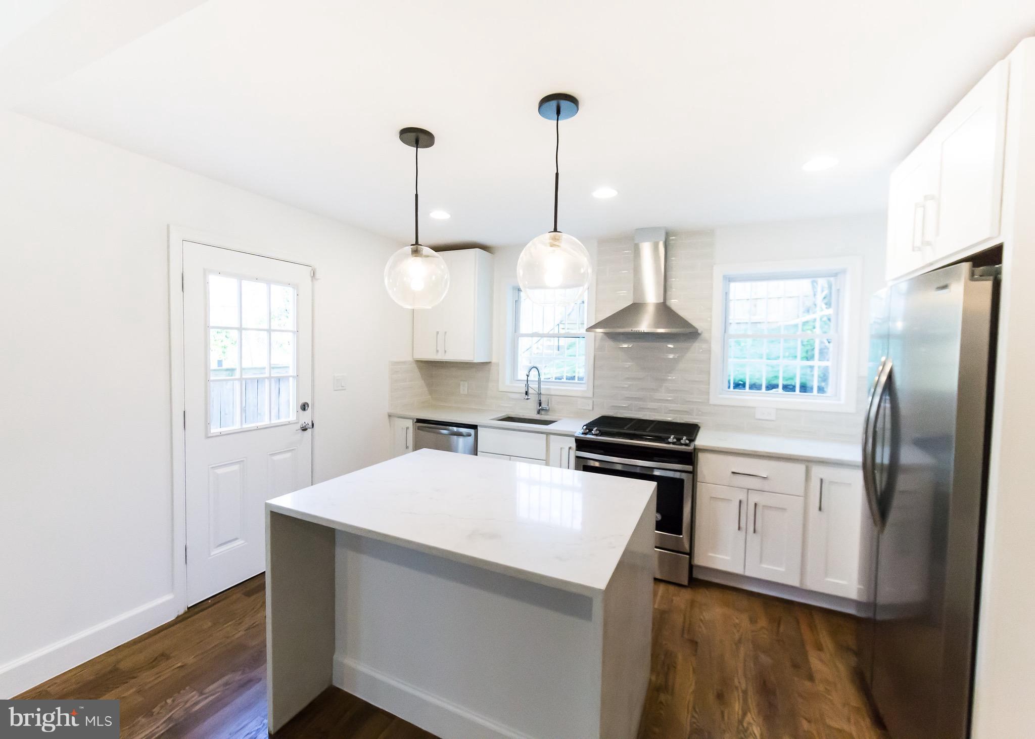 5151 Sheriff Road Northeast Washington, DC 20019 - Photo 4 of 20 a kitchen with stainless steel appliances a stove a refrigerator a chimney a sink and a window