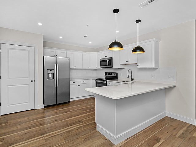 1 Pleasant Street, Unit 205 Cohasset, MA 02025 - Photo 9 of 24 a kitchen with stainless steel appliances granite countertop a sink a stove a refrigerator and island with wooden floor