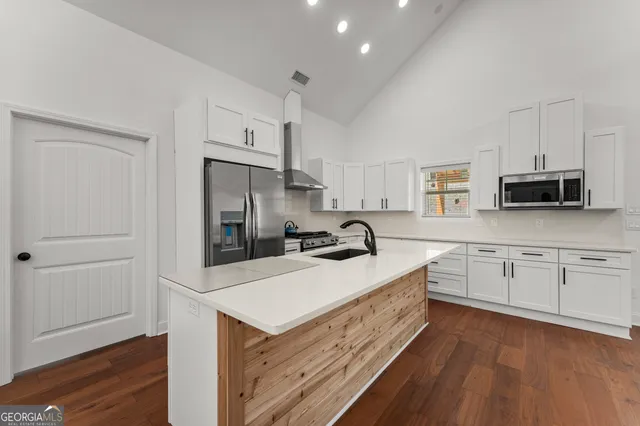 a kitchen with a sink a stove a refrigerator and white cabinets