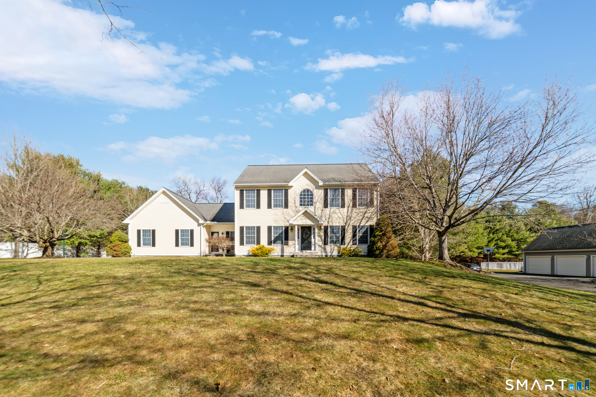 a view of a white house with a big yard and large trees