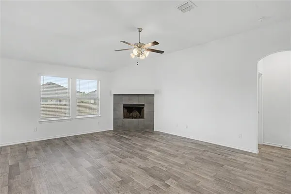 a view of an empty room with chandelier fan and a fireplace