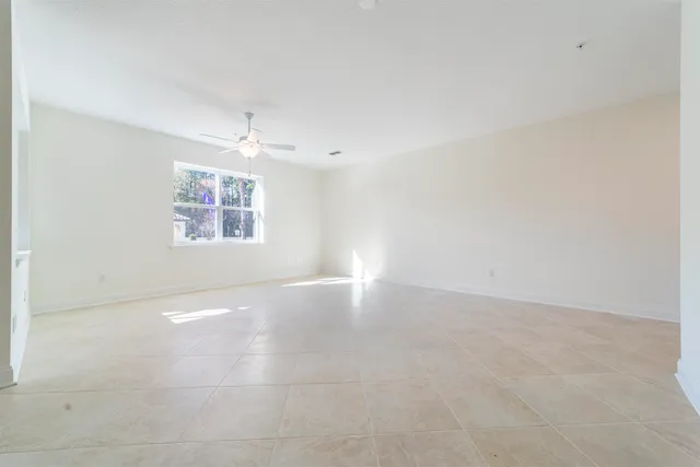 an empty room with windows and ceiling fan