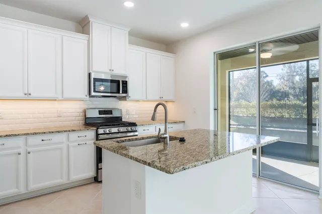 a kitchen with granite countertop a sink stainless steel appliances and white cabinets