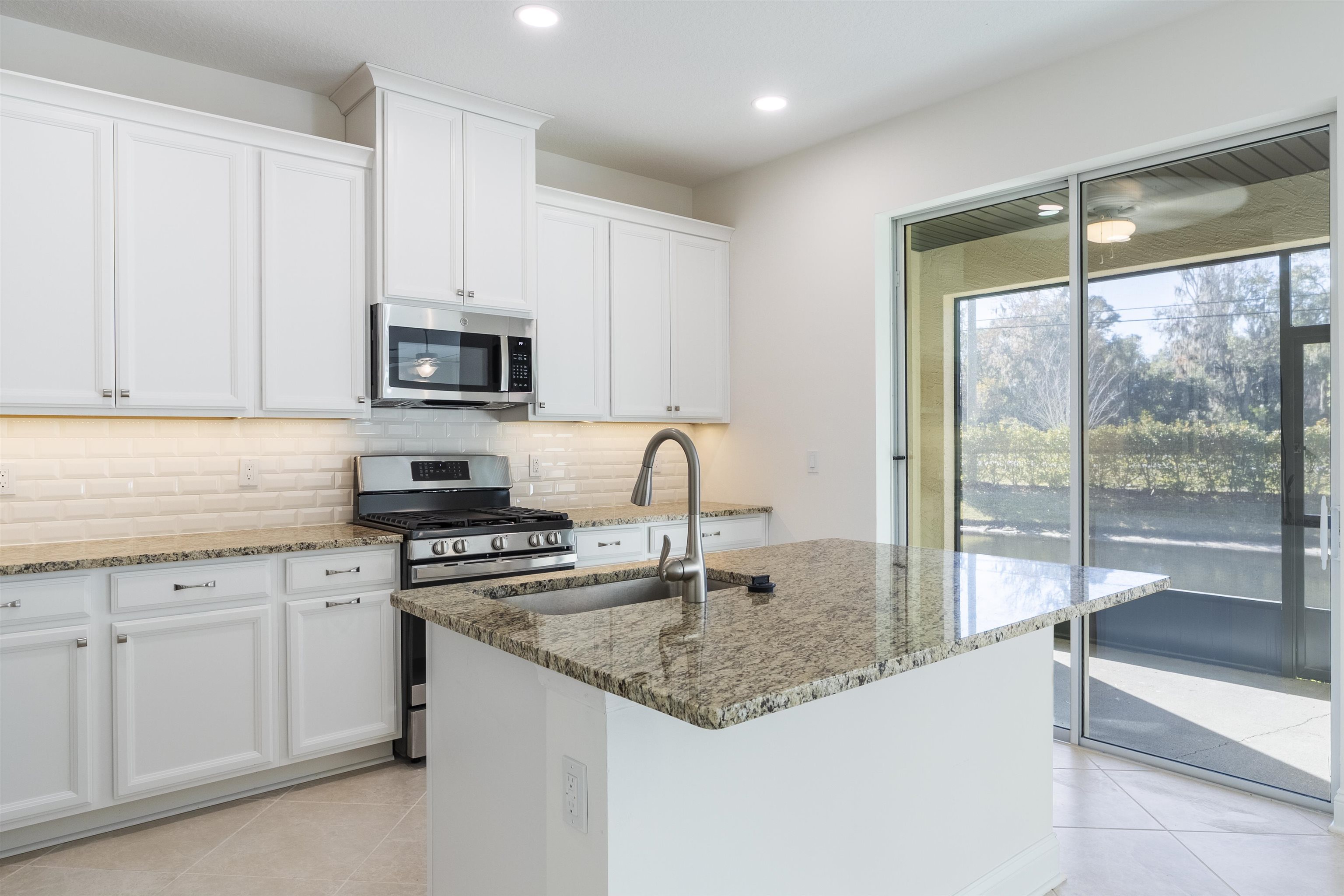 255 Grand Ravine Drive St. Augustine, FL 32086 - Photo 5 of 25 a kitchen with granite countertop a sink stainless steel appliances and white cabinets