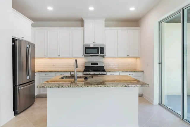 a kitchen with kitchen island a counter top space cabinets and stainless steel appliances