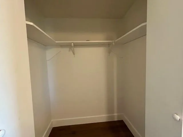 an empty room with wooden floor chandelier fan and windows