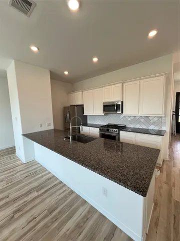 a large kitchen with stainless steel appliances granite countertop a granite counter tops and a stove