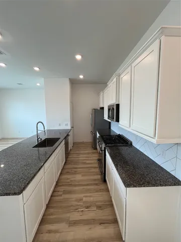 a large kitchen with stainless steel appliances granite countertop a large counter top a stove and a sink