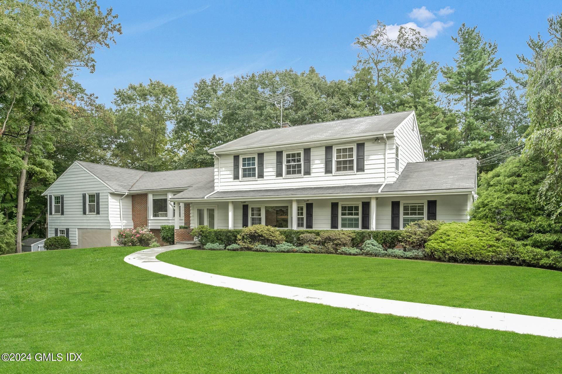 a front view of a house with a garden and trees