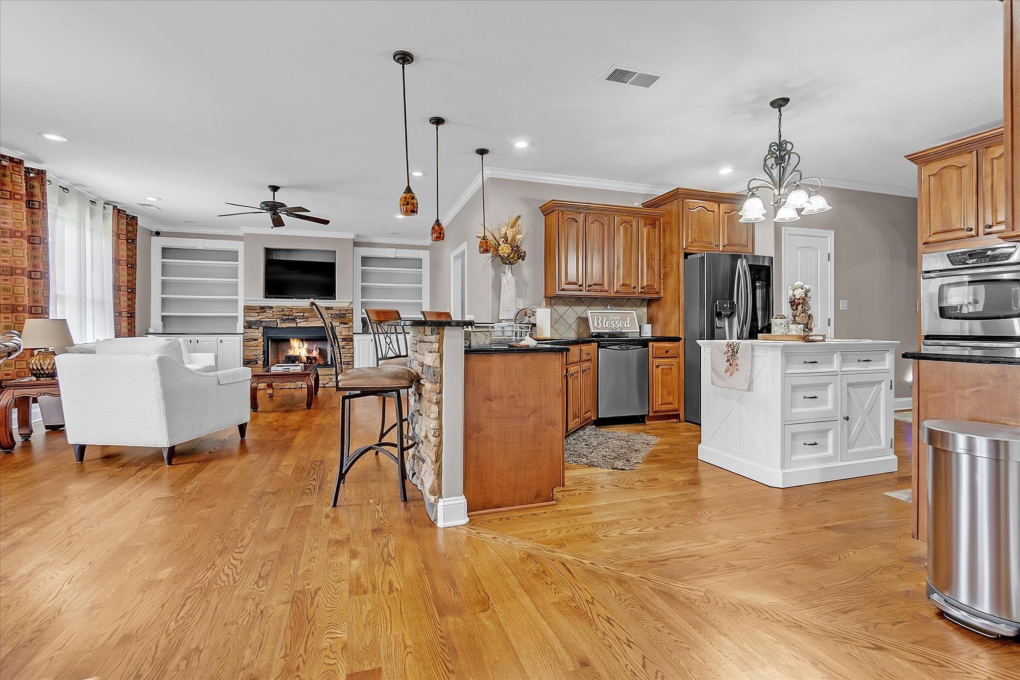 7284 Bucknell Road Millington, TN 38053 - Photo 11 of 35 Hardwood-finish flooring throughout, a kitchen featuring wood cabinetry, a built-in oven, and a white center island