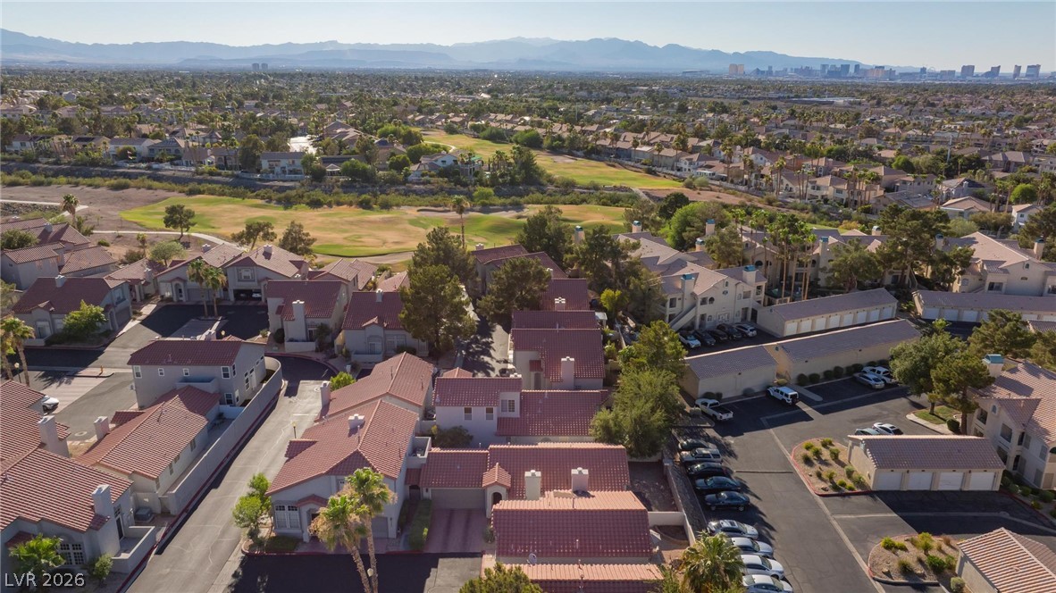2254 Ramsgate Drive Henderson, NV 89074 - Photo 36 of 43 An aerial perspective reveals a vibrant community with red-tiled roofs nestled alongside a verdant golf course, offering distant mountain and city views.