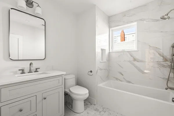 a bathroom with a toilet a sink a mirror a bathtub and vanity