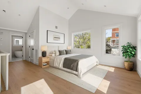 a spacious bedroom with a large bed and a potted plant