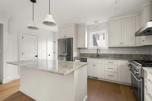 a kitchen with stainless steel appliances granite countertop a sink a stove and refrigerator