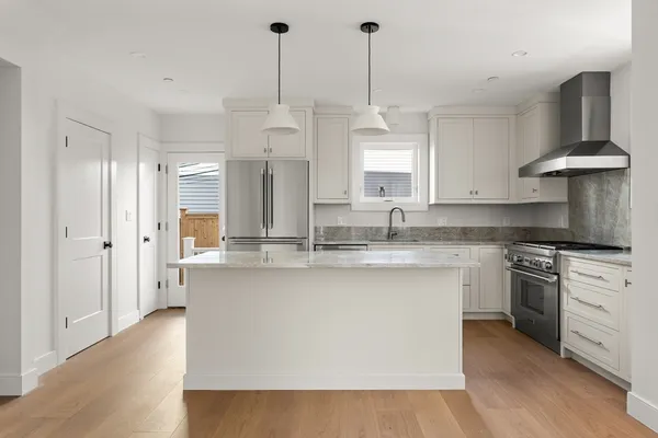 a kitchen with stainless steel appliances granite countertop a sink a stove and a wooden floors