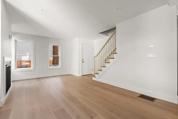 a view of an empty room with wooden floor and windows