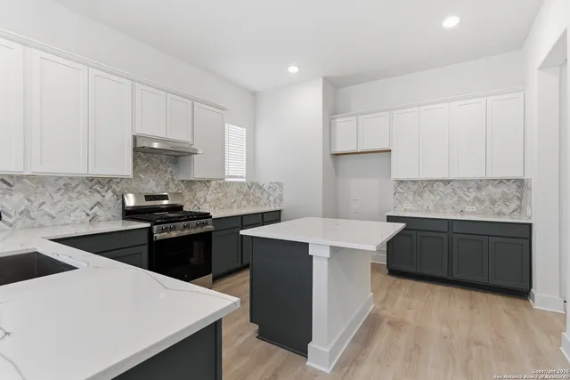 a kitchen with granite countertop white cabinets and black stainless steel appliances
