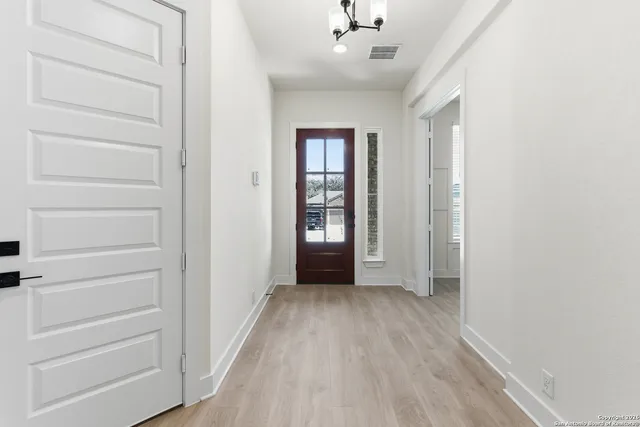 a view of an empty room with window and wooden floor