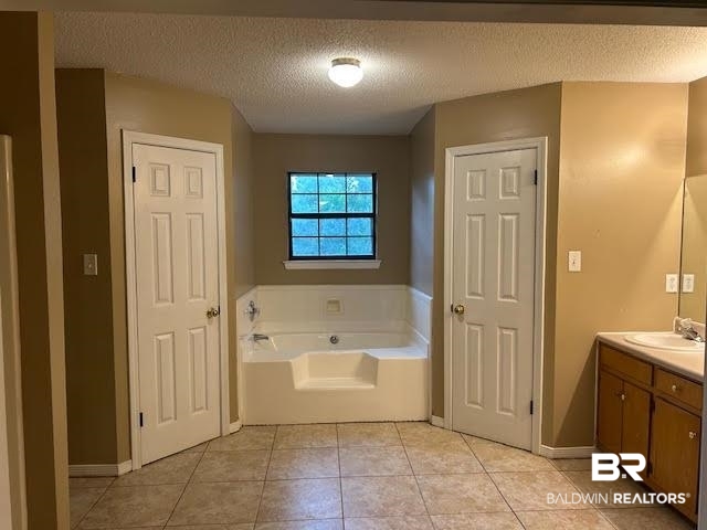 15602 Wrangler Road Summerdale, AL 36580 - Photo 10 of 14 Primary bedroom bath featuring vanity, a bath, a textured ceiling, and tile patterned flooring