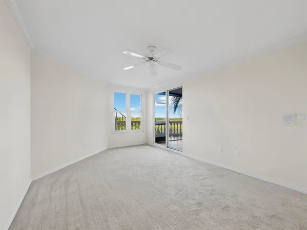 an empty room with chandelier fan and windows