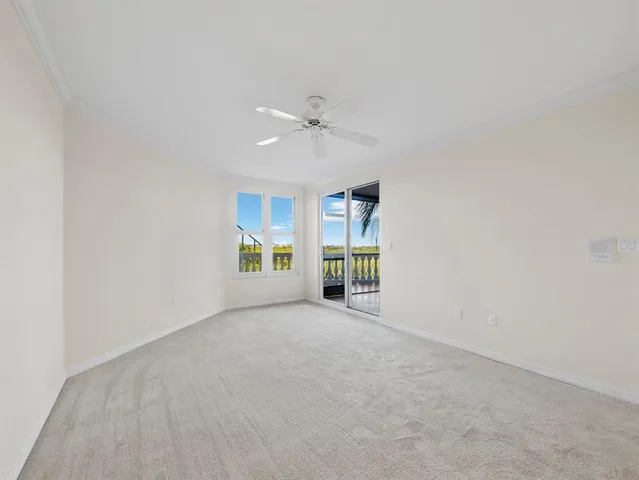 an empty room with chandelier fan and windows