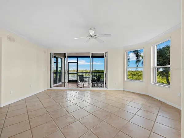 a view of an empty room with window and chandelier fan
