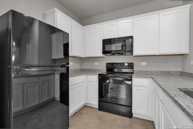 a kitchen with granite countertop white cabinets and stainless steel appliances