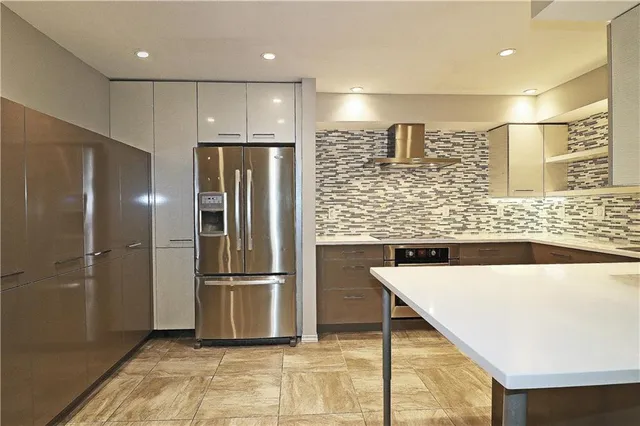 a kitchen with stainless steel appliances kitchen island granite countertop a refrigerator and a sink