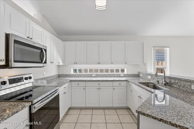 a kitchen with granite countertop a sink a stove a microwave and cabinets