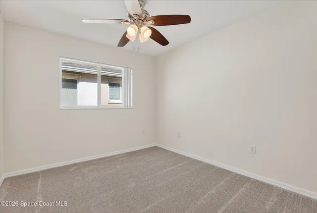 an empty room with a window and a fan