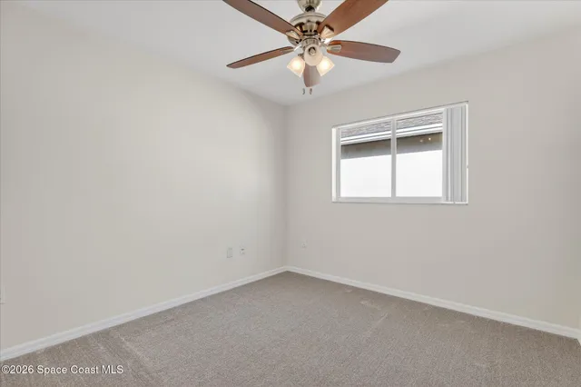 an empty room with a window and a fan
