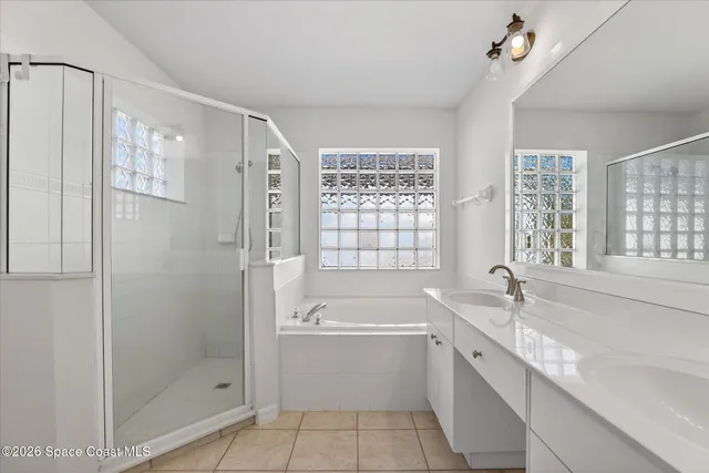 a bathroom with a tub sink shower and two mirror