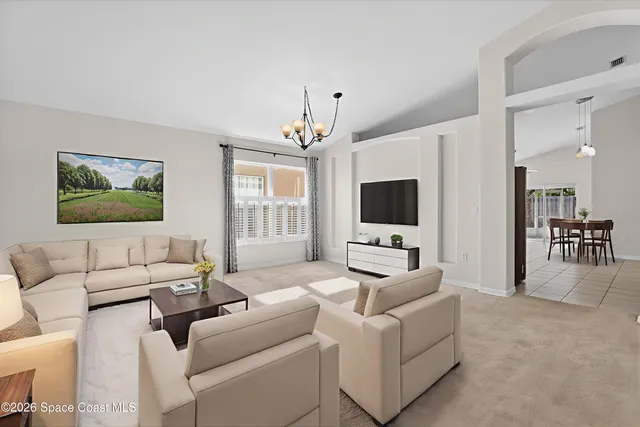 a living room with furniture a flat screen tv and a chandelier