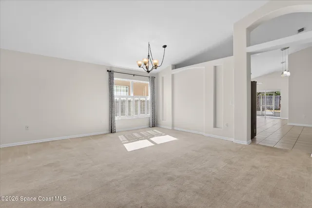 an empty room with chandelier and windows