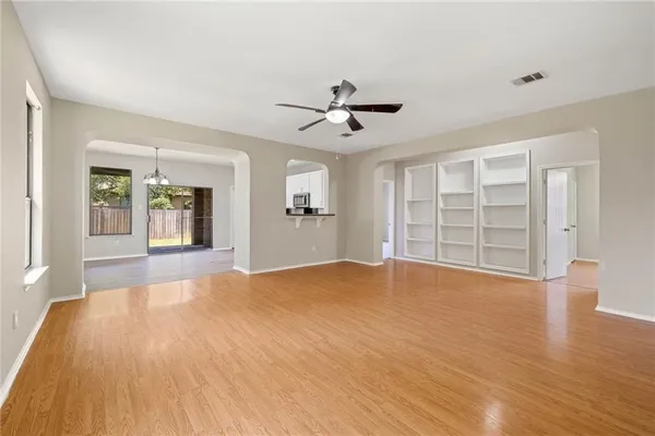 a view of an empty room with a window and a kitchen