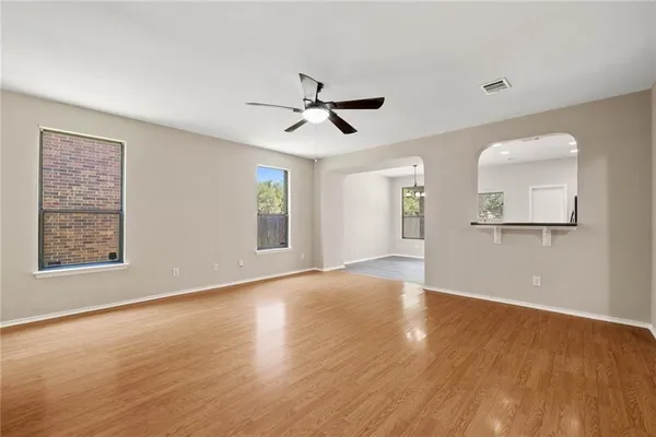 a view of an empty room with window and wooden floor