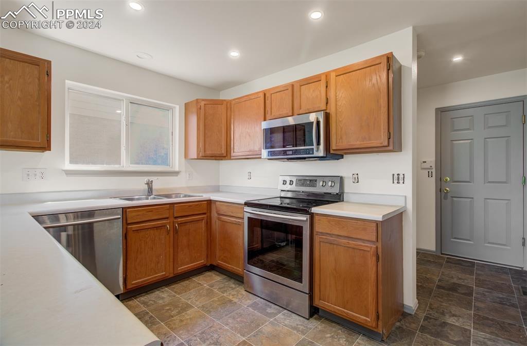 4176 South Himalaya Way Aurora, CO 80013 - Photo 11 of 27 Kitchen with appliances with stainless steel finishes, dark tile patterned flooring, and sink