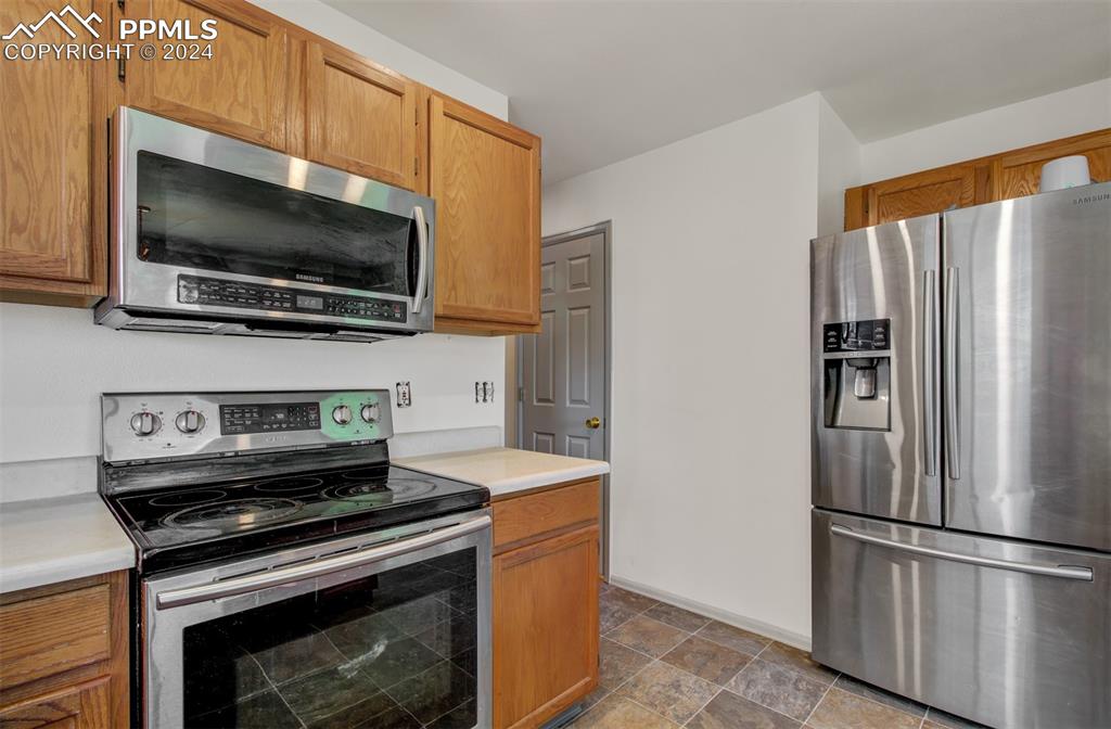 4176 South Himalaya Way Aurora, CO 80013 - Photo 12 of 27 Kitchen with dark tile patterned flooring and stainless steel appliances