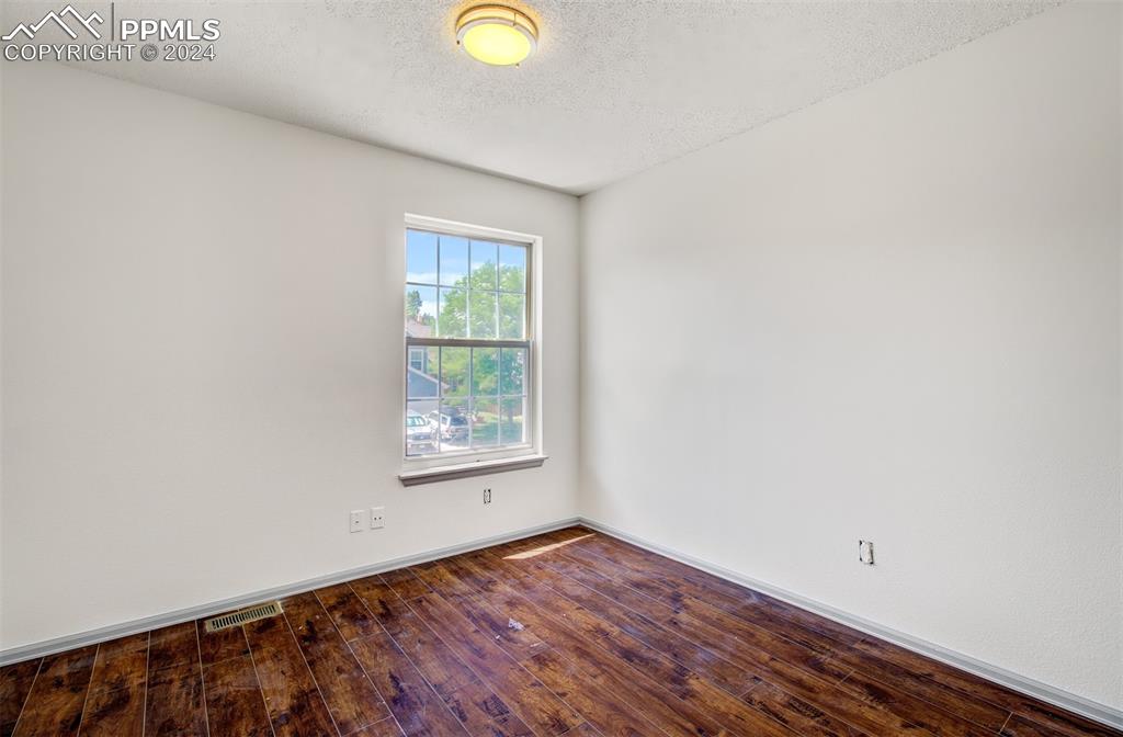4176 South Himalaya Way Aurora, CO 80013 - Photo 19 of 27 Empty room with hardwood / wood-style flooring and a textured ceiling