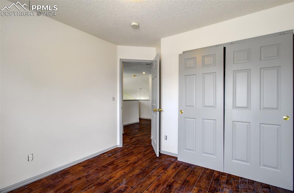 4176 South Himalaya Way Aurora, CO 80013 - Photo 20 of 27 Unfurnished bedroom with dark hardwood / wood-style flooring, a closet, and a textured ceiling