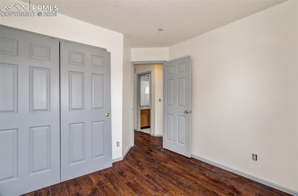 4176 South Himalaya Way Aurora, CO 80013 - Photo 21 of 27 Unfurnished bedroom featuring dark hardwood / wood-style floors, a closet, and a textured ceiling
