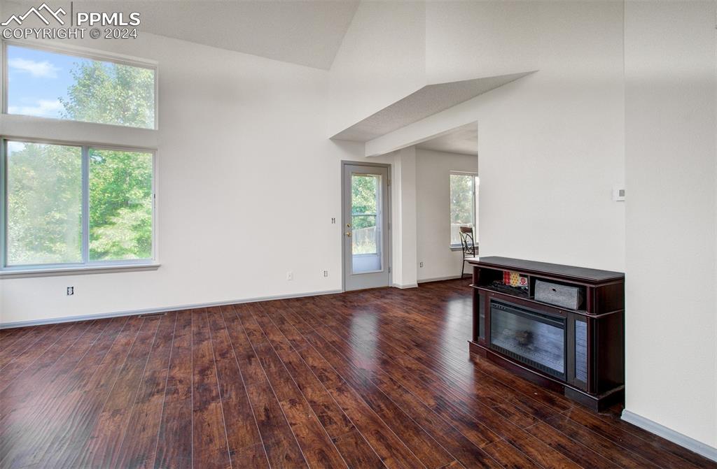4176 South Himalaya Way Aurora, CO 80013 - Photo 4 of 27 Unfurnished living room featuring a high ceiling and dark hardwood / wood-style floors