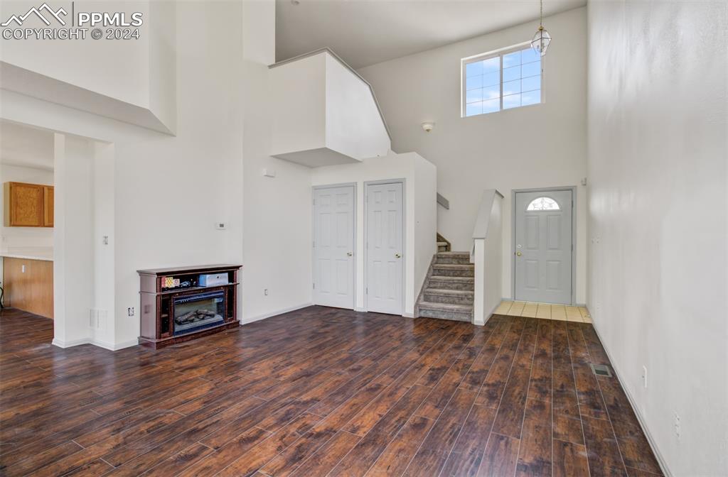 4176 South Himalaya Way Aurora, CO 80013 - Photo 5 of 27 Unfurnished living room featuring dark hardwood / wood-style floors and a towering ceiling