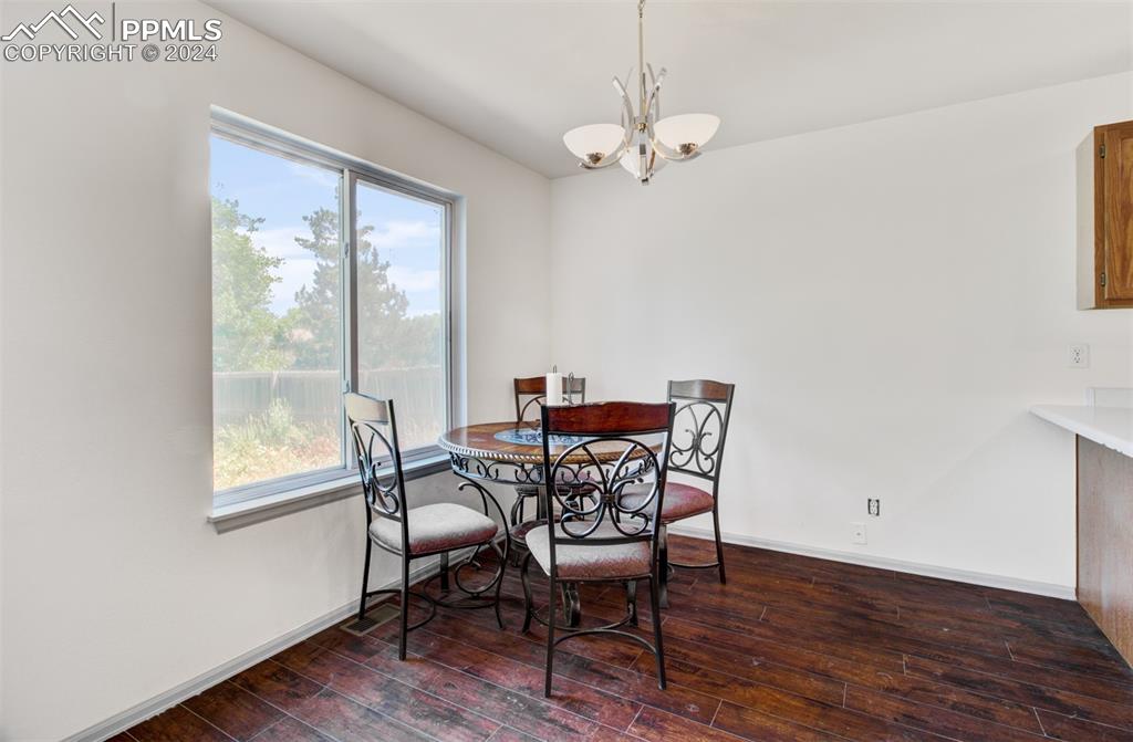 4176 South Himalaya Way Aurora, CO 80013 - Photo 9 of 27 Dining area featuring dark hardwood / wood-style floors, a healthy amount of sunlight, and a chandelier